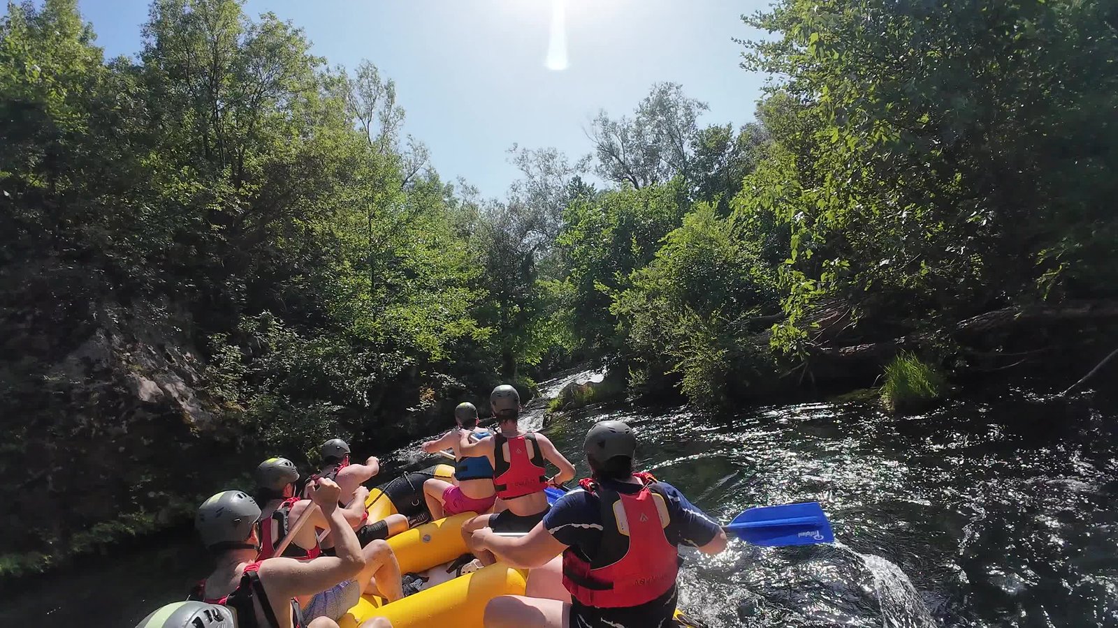 Guided raft with paddlers on the emerald Cetina River below towering limestone canyon walls
