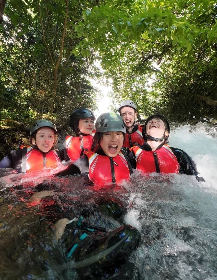 Women in helmets and buoyancy aids laughing in whitewater on the Cetina