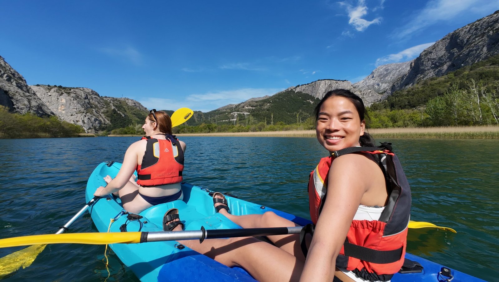 Two women kayaking the Cetina River below the mountains near Omiš
